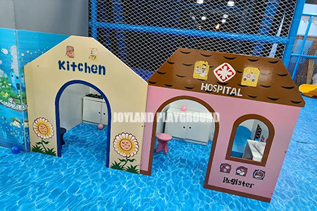 Children enjoying role-play activities in a themed playhouse in an indoor playground.