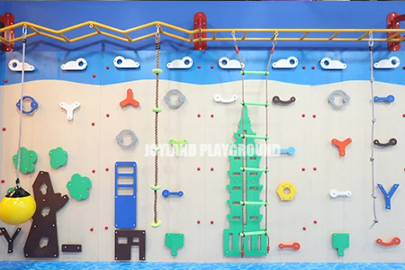 Children climbing on a colorful indoor climbing wall in India.