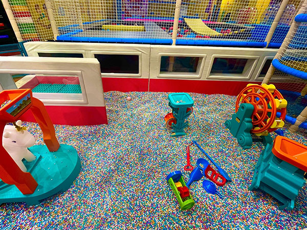 Children playing with colored sand in a themed indoor sand play zone