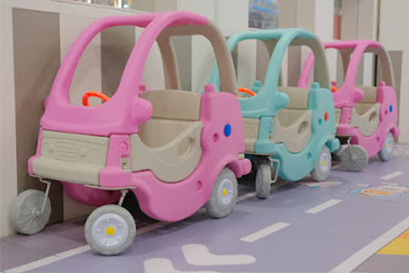 Children enjoying ride-on cars in indoor playground equipment for home venues.